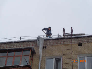 Удаление сосулек с крыши дома.